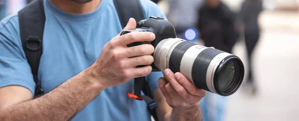 Photographer takes photographs with dslr camera in a city.