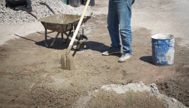 İşçiler inşaat alanında kürekle beton hazırlıyorlar..