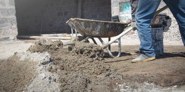 İşçiler inşaat alanında kürekle beton hazırlıyorlar..