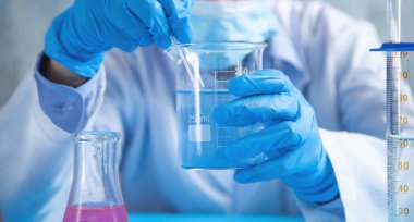 Laboratuvarda şişeyle çalışan bir kız..