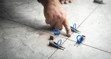  El, fayansların arasına plastik bir ataç yerleştirir..