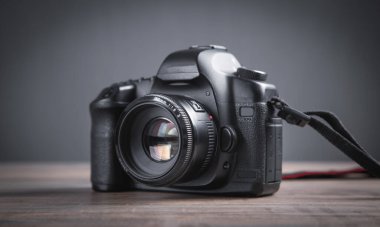 Ahşap masada profesyonel DSLR kamerası var..