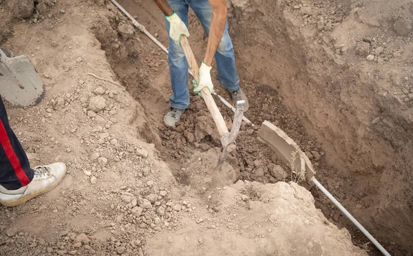 Caucasian worker digging a hole.