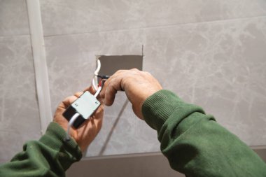 Elektrikçi bir evin tavanında elektrik tesisatı yapıyor..