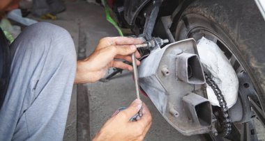 Beyaz adam garajda motosikletini tamir ediyor..