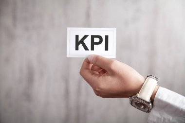 KPI sözcüğünü kağıt üzerinde gösteren insan eli.