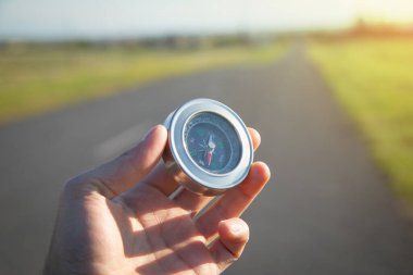 Yol arka planında pusula tutan gezgin.