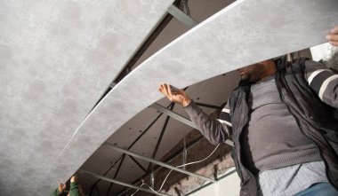 İnşaat işçisi asılmış tavanı monte ediyor.