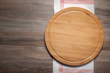 Boş pizza tahtası ve ahşap arka planda kumaş masa örtüsü.