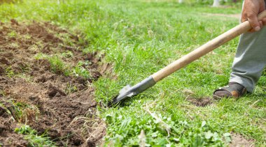 Çiftçi bahçede kürekle toprak kazıyor..