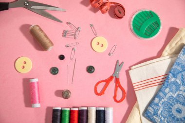 Pembe kağıt arkaplanda dikiş araçları.