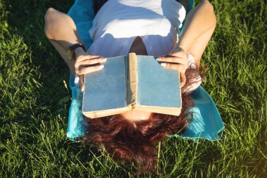 kız kitap okuma çim üzerinde yalan.