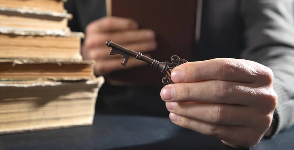 Man holding old key with a book.