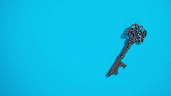 Old antique key on the blue background.