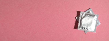 Pembe arka planda prezervatif. Metnin için boşluk