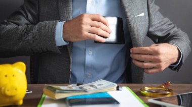 İşadamı onun deri cüzdan takım elbise cep içine çeker.