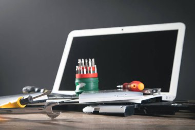Masada İngiliz anahtarı ve tornavidayla kırılmış bir laptop. Bilgisayar onarım servisi