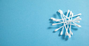 Mavi arka planda kulak temizleme için pamuk tomurcukları ya da çubuklar.