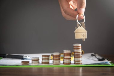 Erkek el bozuk para yığınının üzerinde evin anahtarlarını gösteriyor..