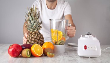 Meyveleri elektrikli mikserle karıştıran adam.