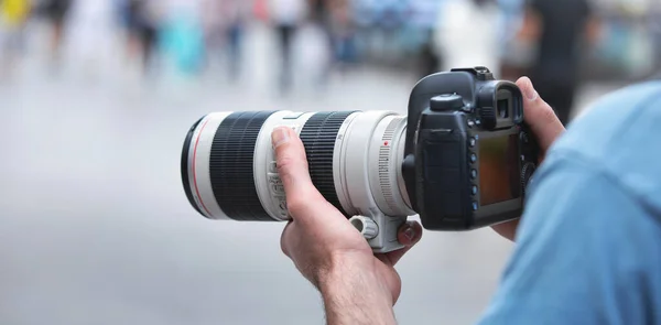 Photographer takes photographs with dslr camera in a city.