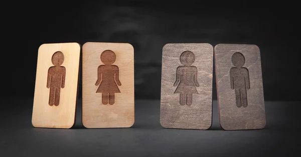 Men and Women wooden symbols on the black background.
