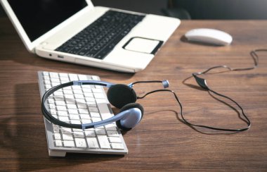 Mavi arkaplanda müşteri hizmetleri kulaklığı, bilgisayar klavyesi ve iş nesneleri.