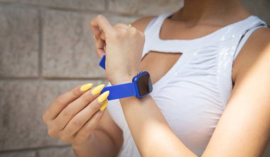 Mavi akıllı saat takan kadın.