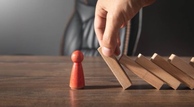 Erkek el, tahta blokların insan figürünün üzerine düşmesini engelliyor..