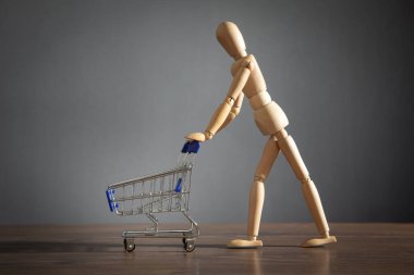 Alışveriş arabası olan tahta insan figürü..