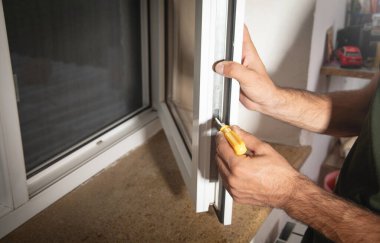  İşçi, pencereyi tornavidayla onarıyor. Eve yeni plastik pencere takılıyor