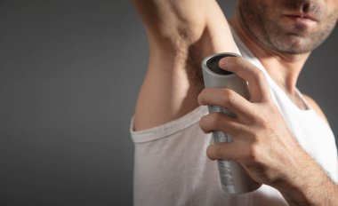 Genç adam koltuk altına deodorant sıkıyor..