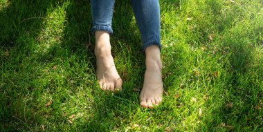 Kadın bacakları rahatlar yeşil çimlerde hisseder.