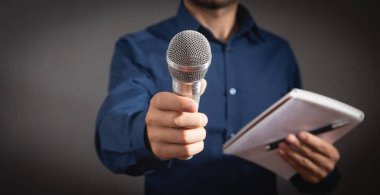 Beyaz gazeteci elinde mikrofon, not defteri ve kalem tutuyordu..
