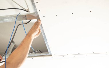 İnşaat işçisi evde tavan üzerinde çalışıyor..