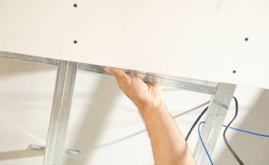 İnşaat işçisi evde tavan üzerinde çalışıyor..