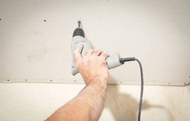 Matkap tornavidalı bir işçi vidayı alçıpana çeviriyor..