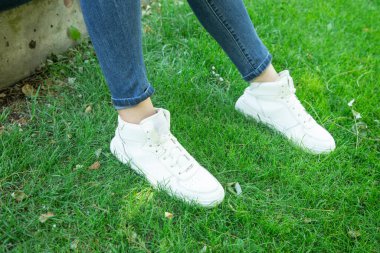 Yeşil çimenlerin üzerinde şık ayakkabılar giyen genç bir kadın..