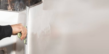 İşçi duvara macun yapıştırıyor. Ev yenileniyor. 