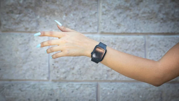 Female hand with a black smart watch.