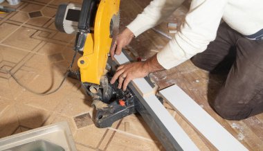 Mobilyanın bir kısmını kesme makinesiyle kesen işçiler.