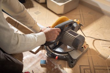 Mobilyanın bir kısmını kesme makinesiyle kesen işçiler.