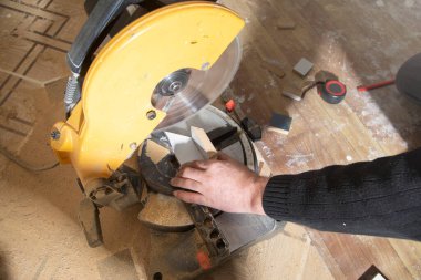 Mobilyanın bir kısmını kesme makinesiyle kesen işçiler.