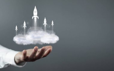 Adam bulutların üzerinde uçan roketler gösteriyor. İş Başlangıcı