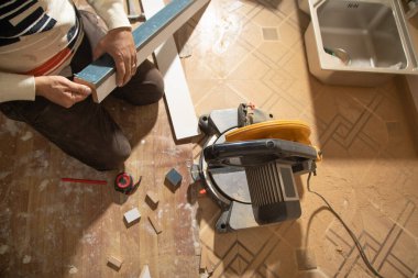 Mobilyanın bir kısmını kesme makinesiyle kesen işçiler.