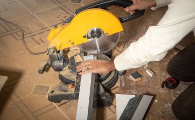 Mobilyanın bir kısmını kesme makinesiyle kesen işçiler.