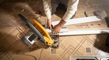 Mobilyanın bir kısmını kesme makinesiyle kesen işçiler.