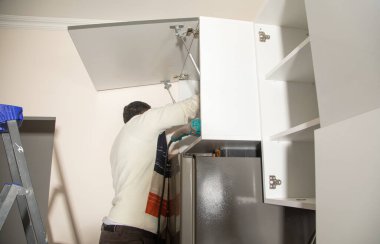 Yeni mutfak mobilyalarının işçiler montajı.