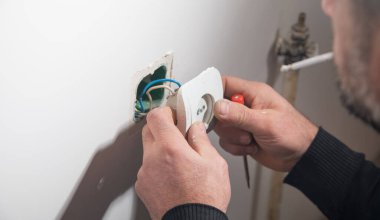 Elektrikçi eve bir duvar soketi takıyor.
