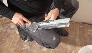İşçi spatula tutuyor. Ev yenileniyor. 